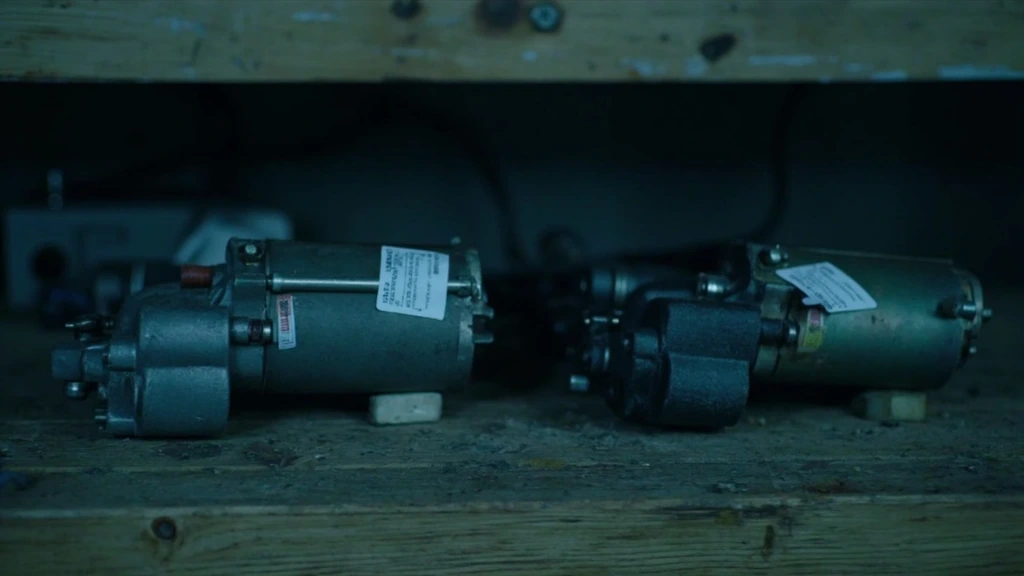 Old and new replacement starter motors on a workbench.