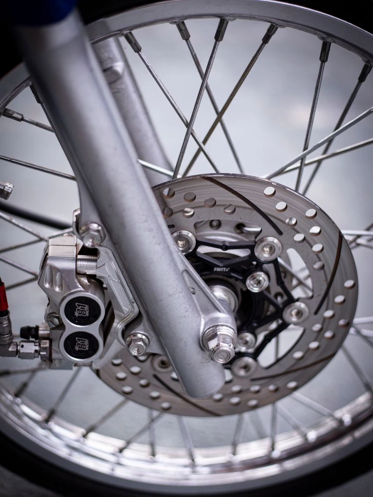 Pre-bagged disc brake conversion kit with caliper rotor and stainless lines on a workbench
